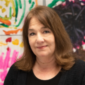 A person with long hair standing in front of a colorful painting